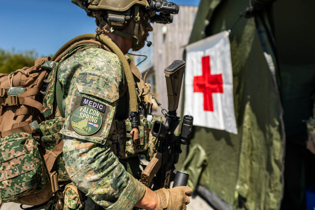 Bewapende medic loopt naar ingang Role 1 ziekenhuis.