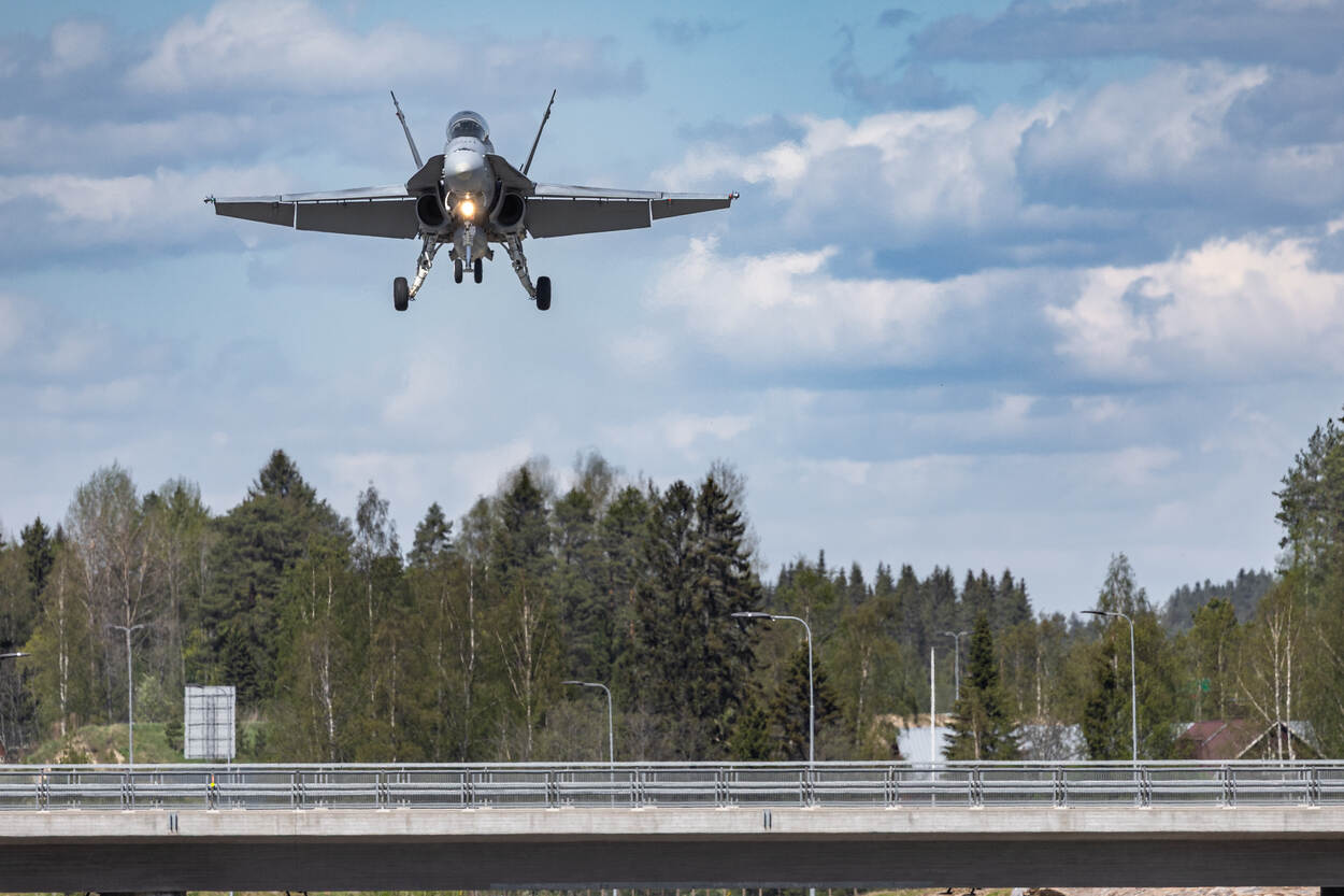 Een Finse F/A-18 frontaal vlak boven een viaduct, op de achtergrond bebossing.