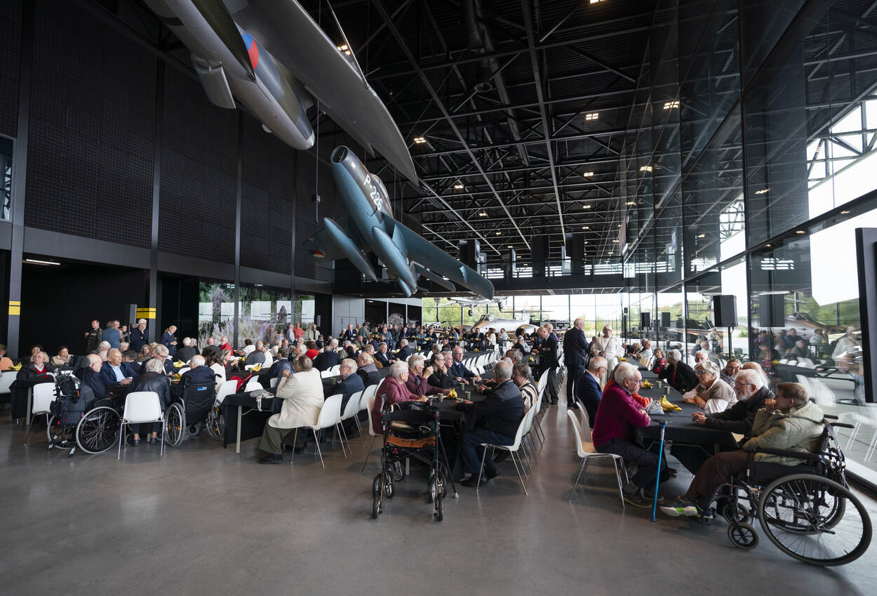 Overzicht in het Nationaal Militair Museum met veel bezoekers aan lange tafels.