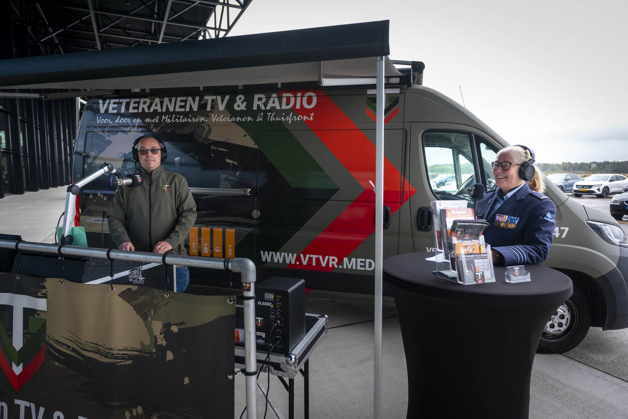 Een luchtmachtmilitair staat bij de rijdende studio van Veteranen TV e Radio.