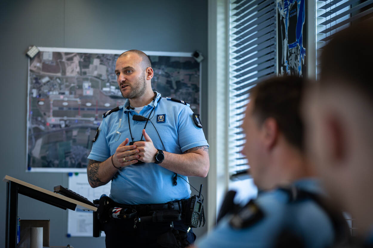 Een marechaussee spreekt voor een groep deelnemers, die deelneemt aan de oefening.