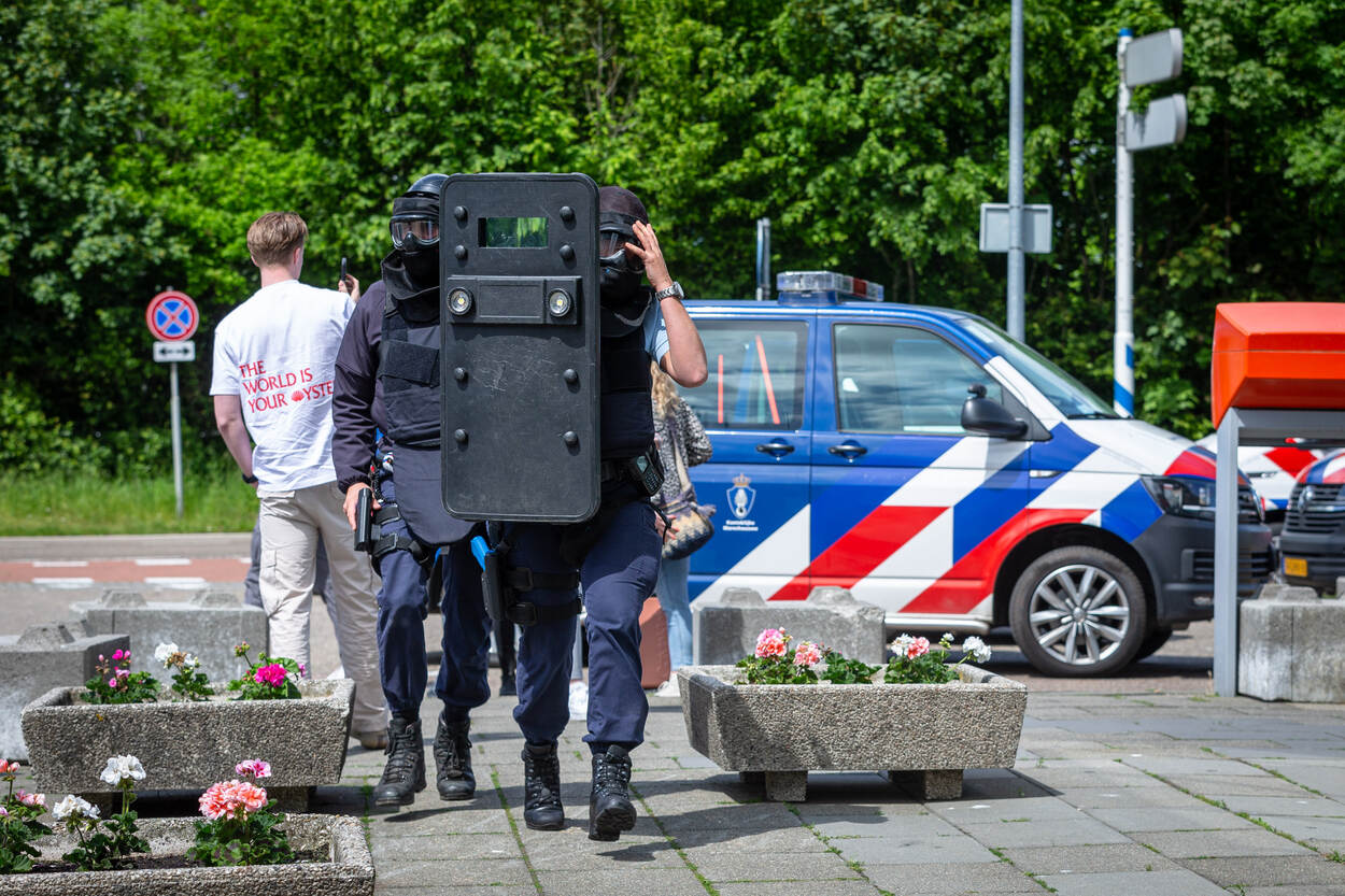 Een marechaussee verplaatst zich met een schild voor zijn lichaam.