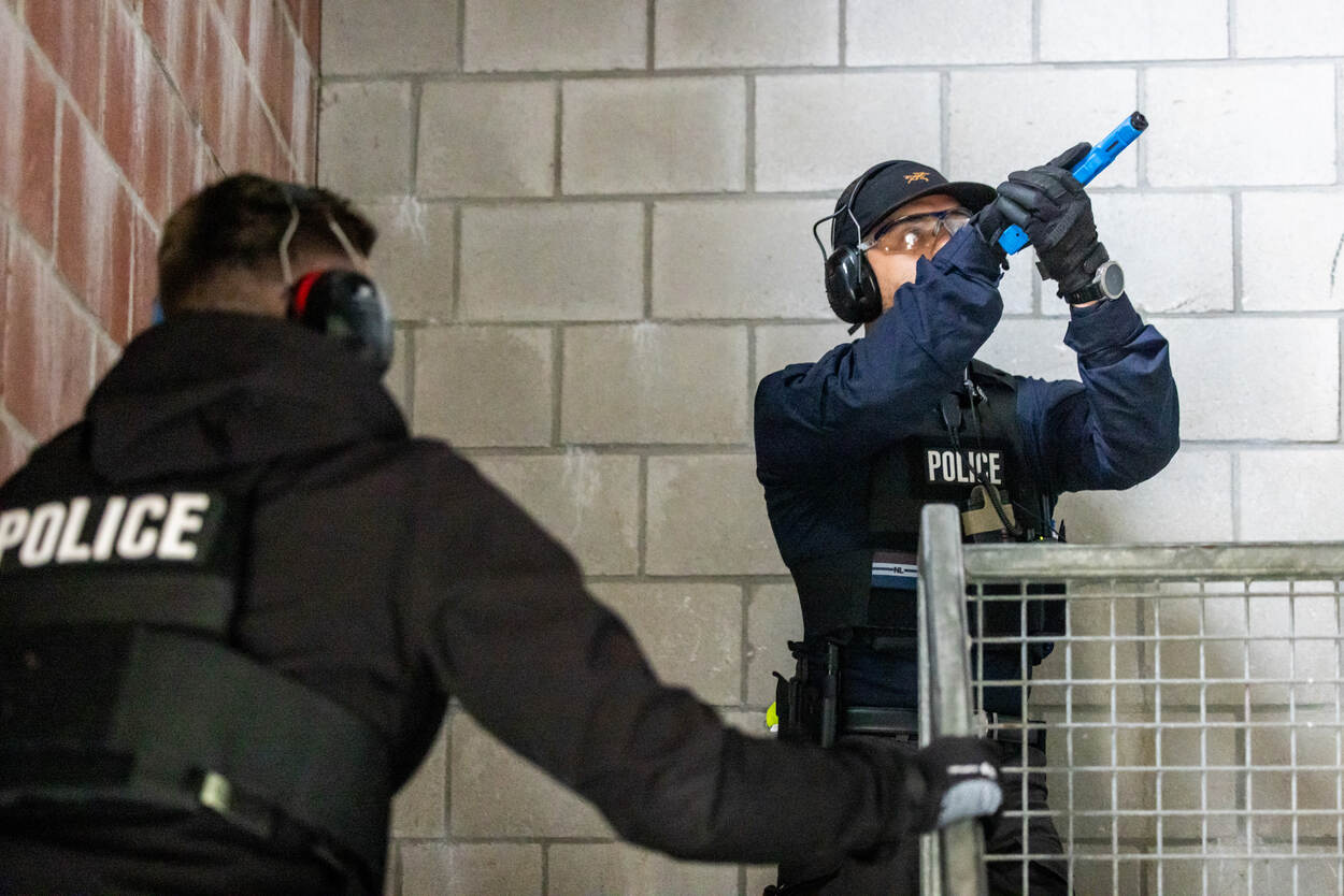 Persoonsbeveiligers zuiveren met getrokken wapen een gebouw.