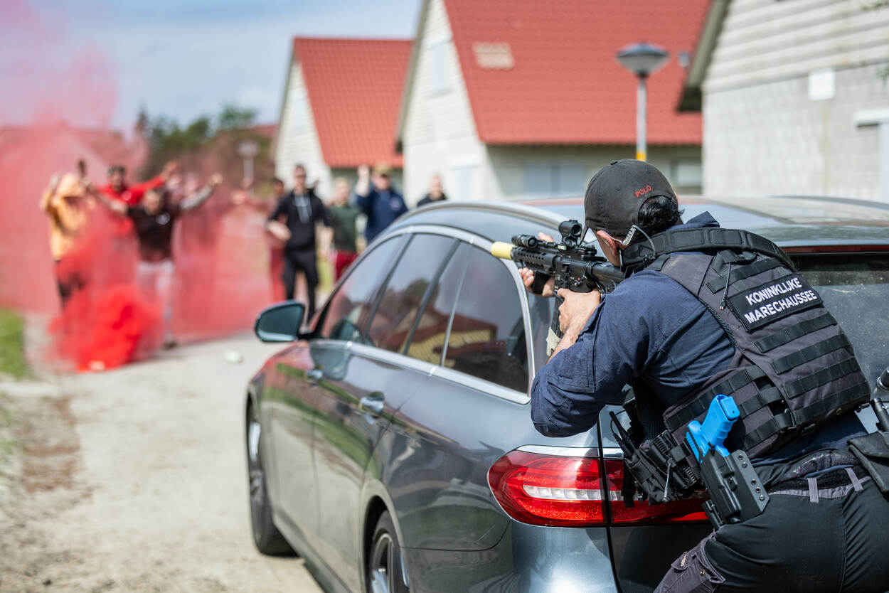 Een persoonsbeveiliger houdt een boze menigte onder schot.