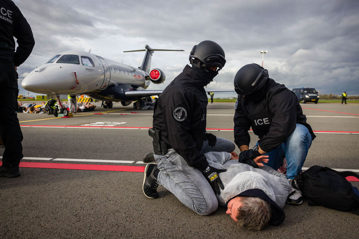 Marechaussees houden een actievoerders op de grond tijdens een aanhouding.