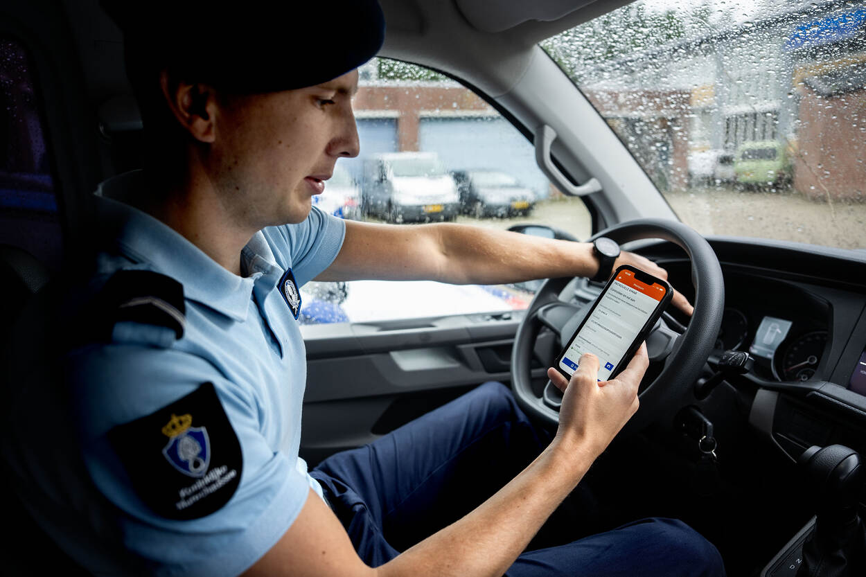 Machiel zit in een dienstvoertuig en vergelijkt de gegevens in de App met de info in het dashboard van de wagen.