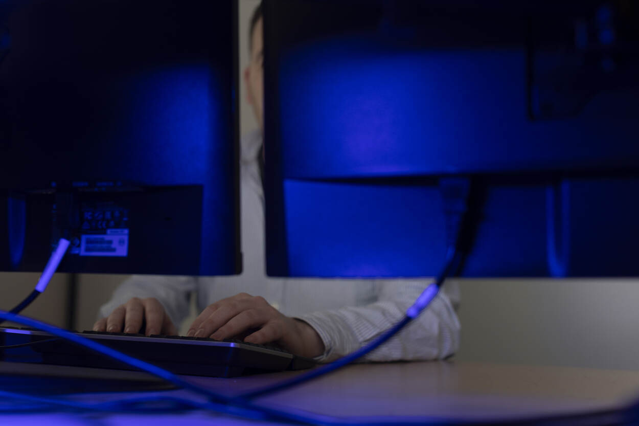 Een persoon zit achter 2 beeldschermen.