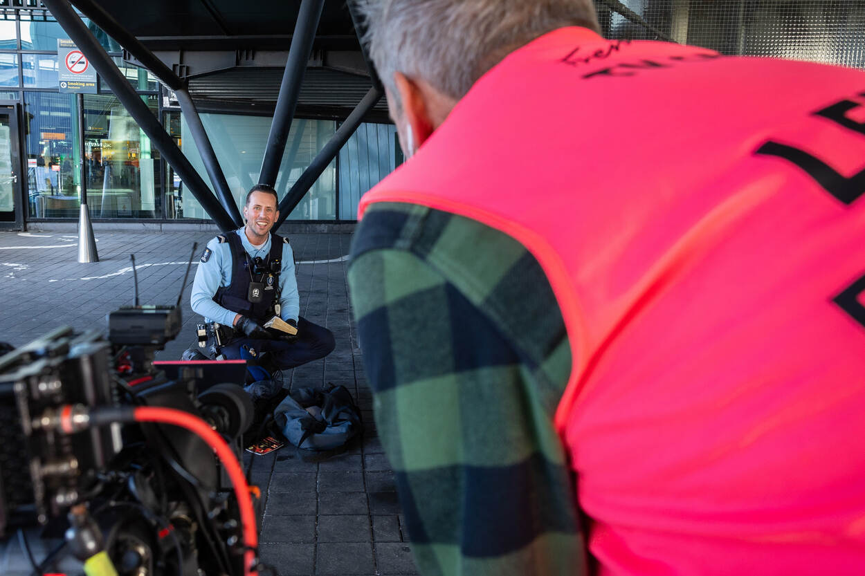 Wachtmeester KMar voor de camera op Schiphol.