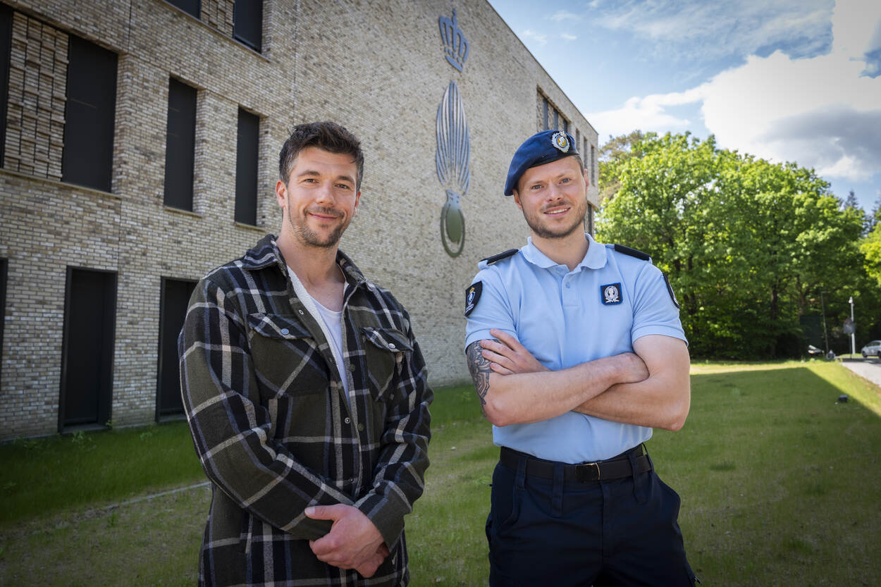 Twee mannen staan naast elkaar op het gras voor kantoorgebouw.