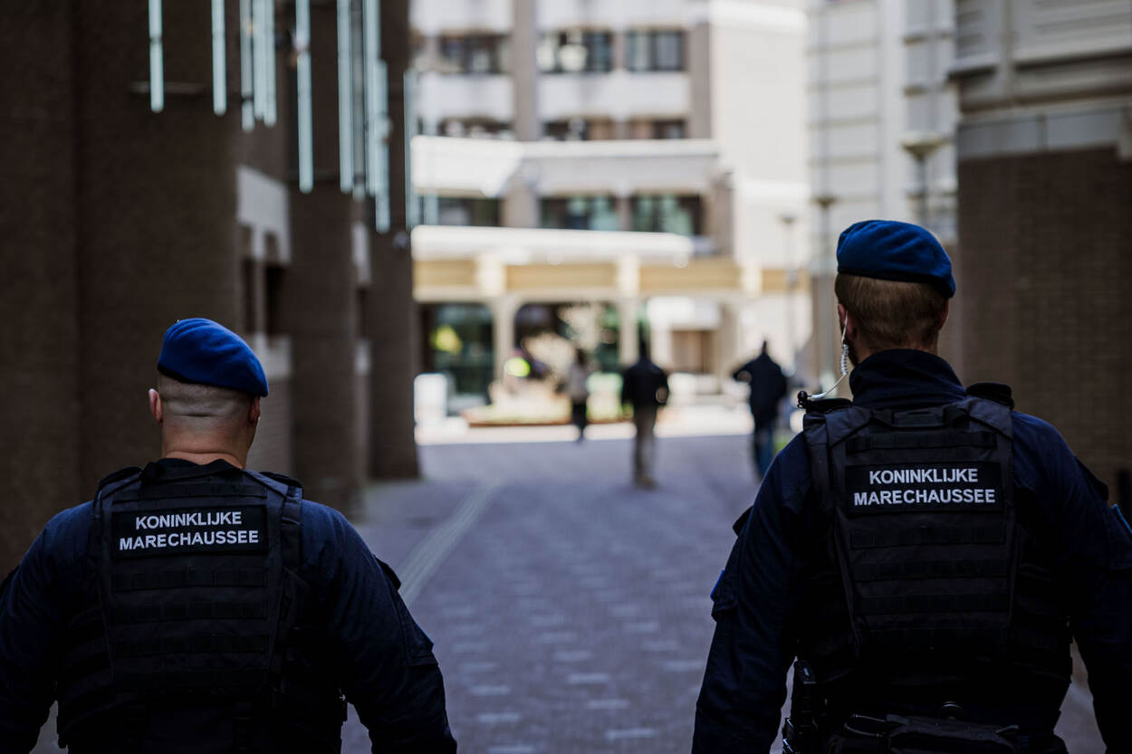 2 beveiligers van de marechaussee lopen gezamenlijk door een smalle straat.