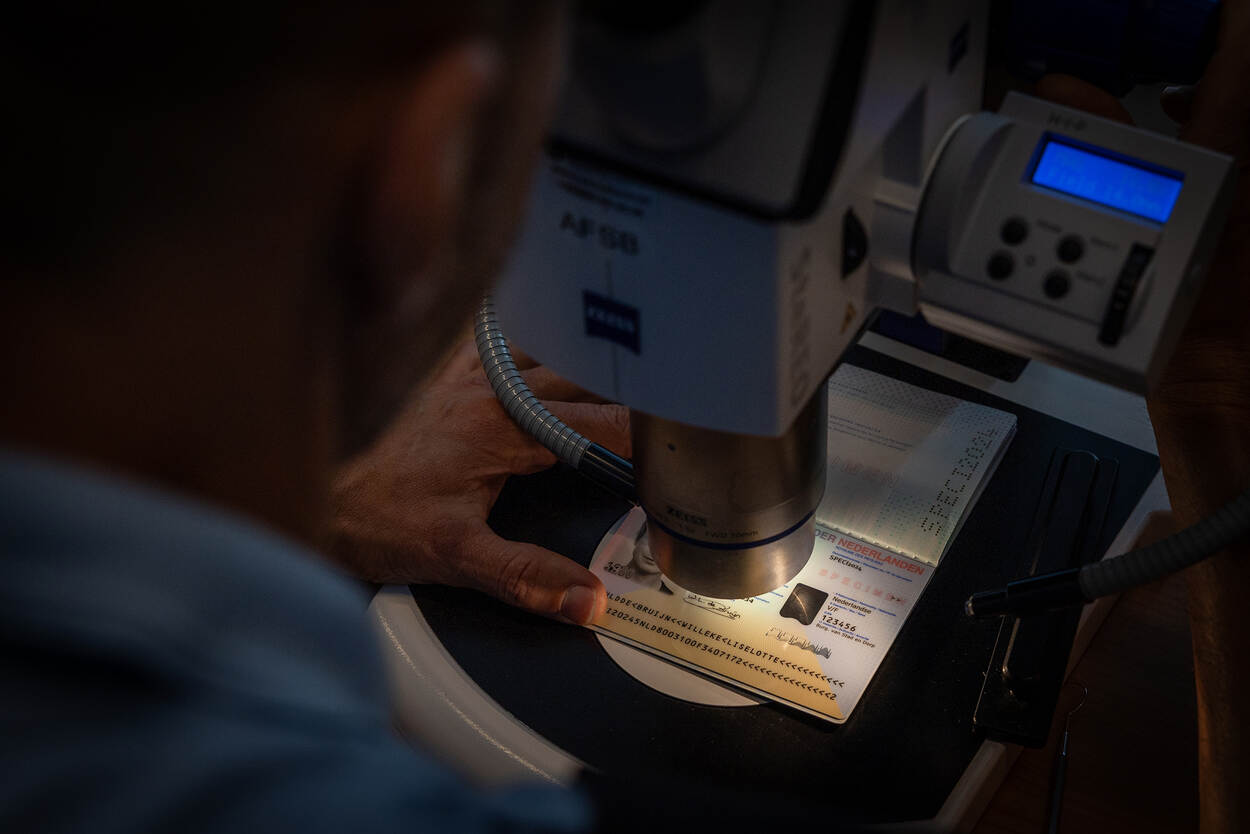 Een paspoort wordt minutieus onder een microscoop gecontroleerd.