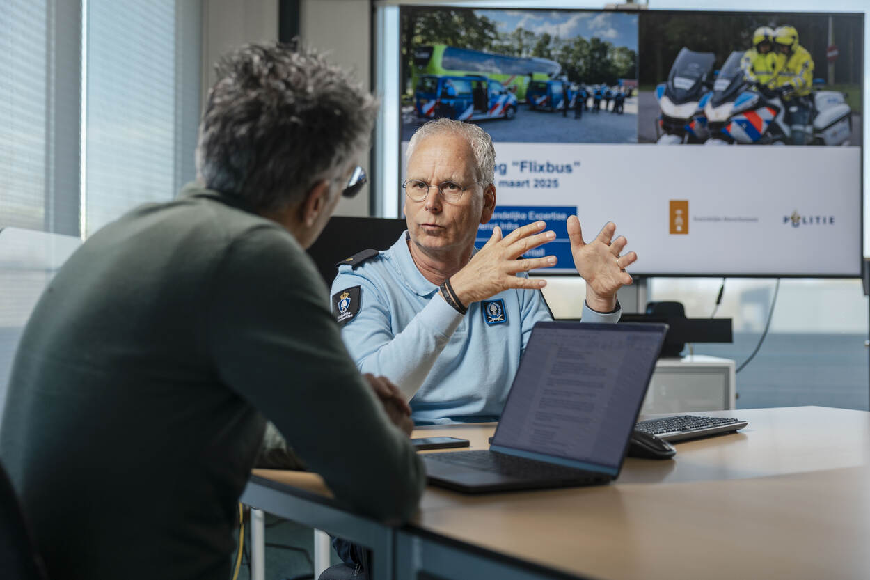 Twee mannen in gesprek aan kantoortafel.