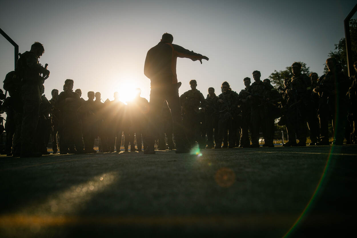 De groep wordt door een sportinstructeur toegesproken.