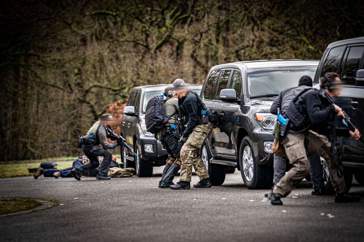 Drie zwarte auto’s staan naast elkaar opgesteld, daarachter zwaarbewapende BSB’ers die dekking zoeken. Vanachter de auto’s vandaan schieten ze op hun doel.