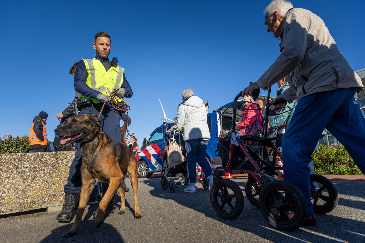 Een douanemedewerker met een speurhond controleert passanten in de Eemshaven.