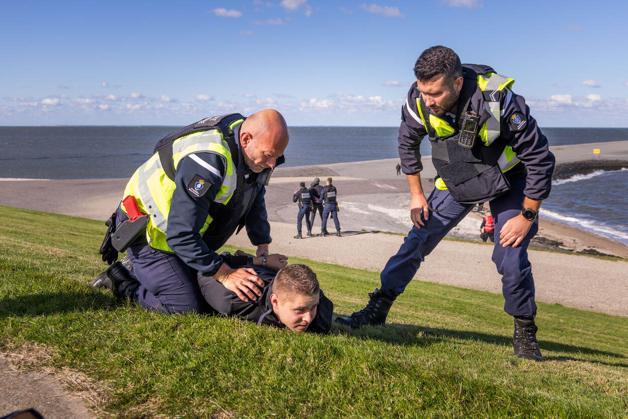Een marechaussee boeit een verdachte.