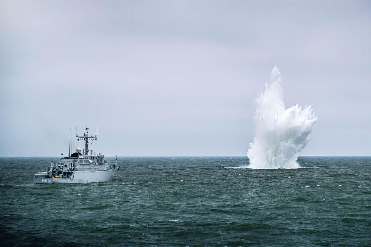 Zr.Ms. Urk en een waterzuil van een ontploffende zeemijn.