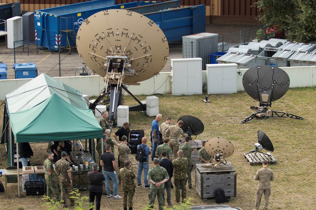 Meerdere satcom-schotels en apparatuur met een aantal militairen.
