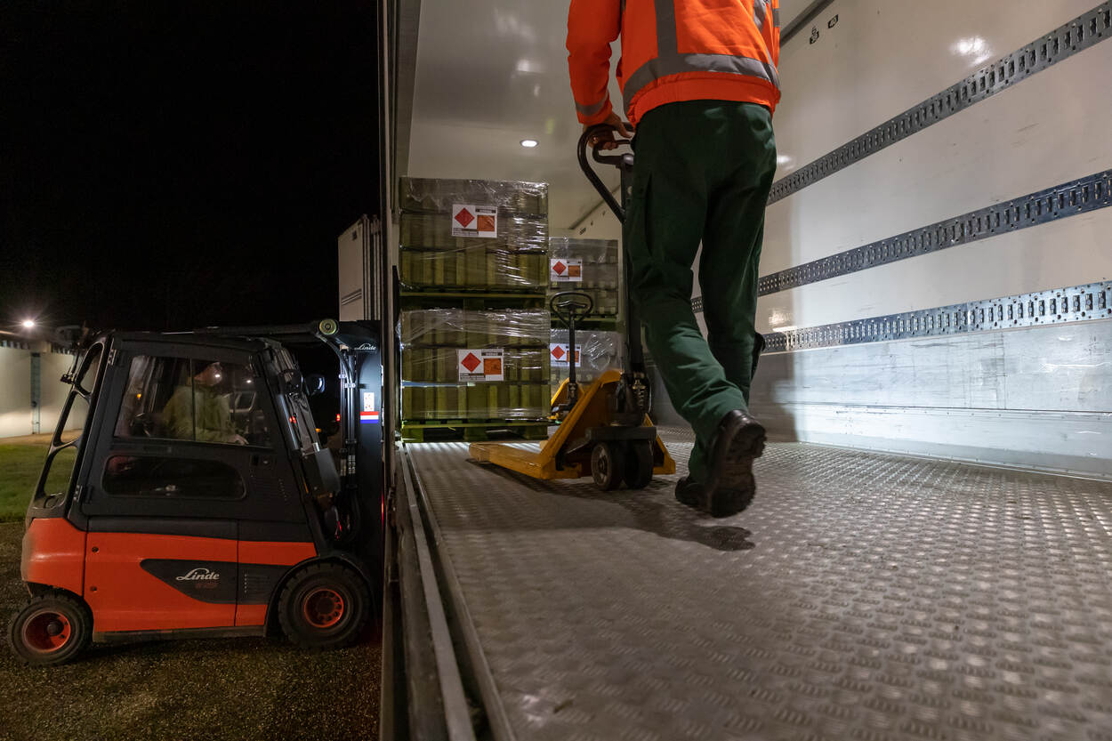 Medewerker Munitiebedrijf in vrachtwagen met munitie en een heftruck.