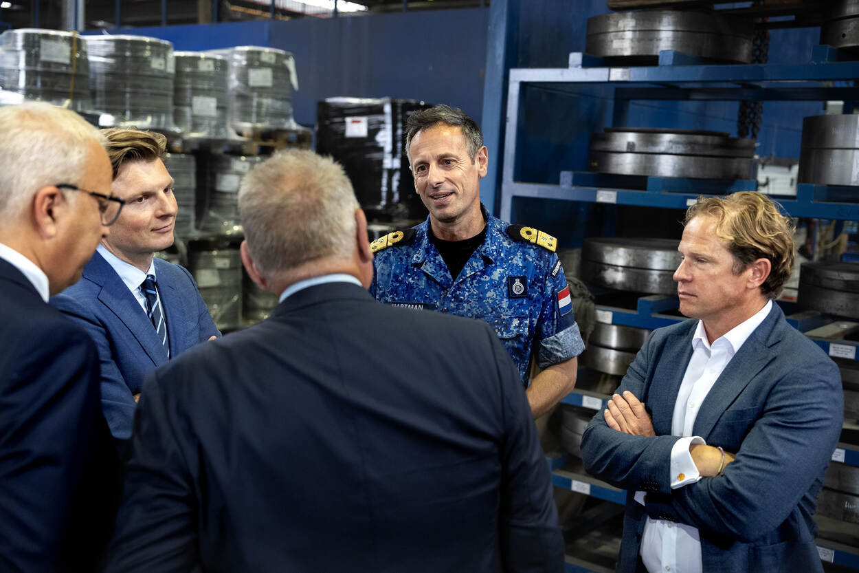 Viceadmiraal Jan Willem Hartman tussen de minister en staatssecretaris van Defensie in gesprek met mensen van Van Halteren.