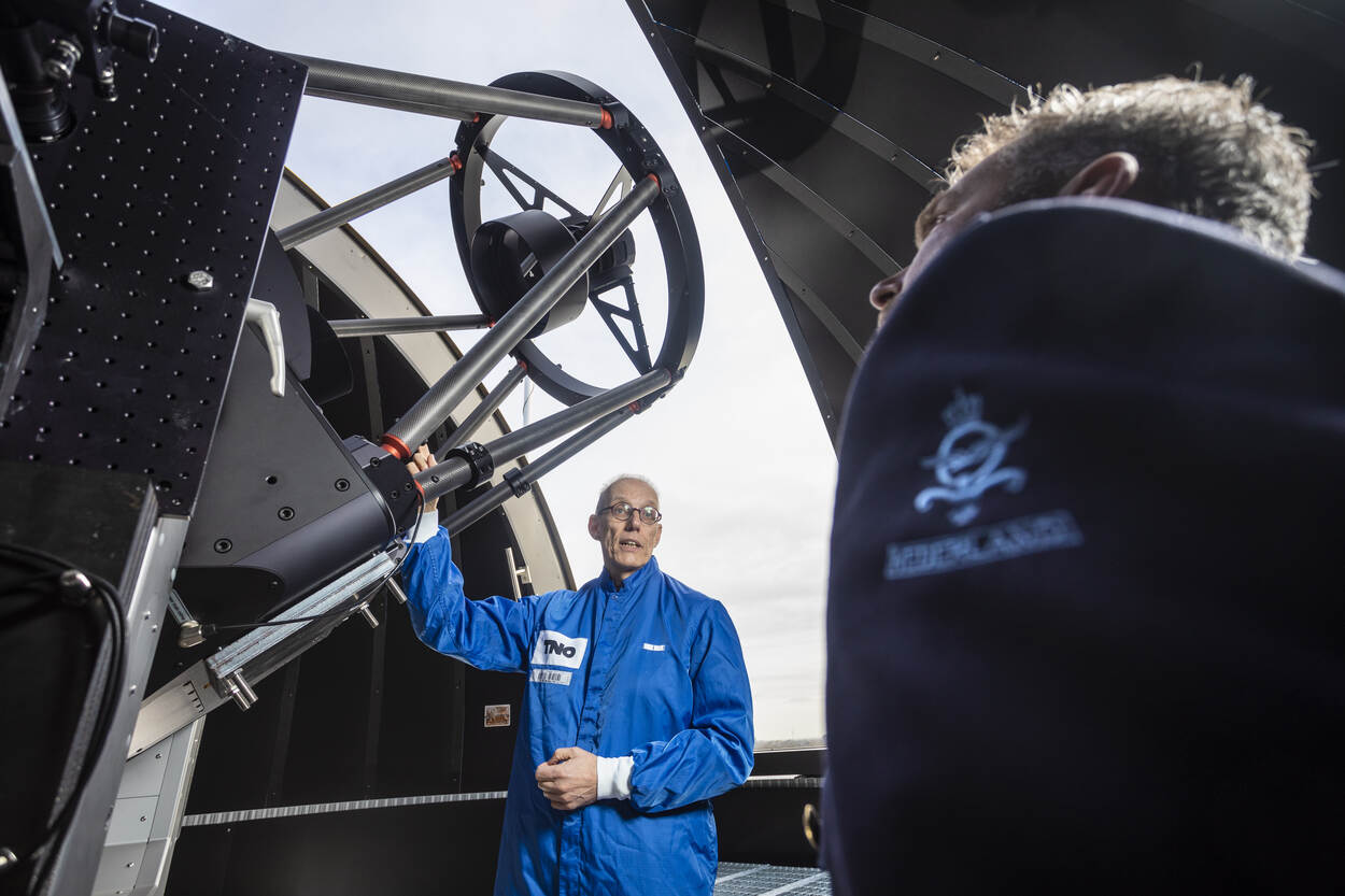 TNO-medewerker in blauwe overall naast laserontvanger.