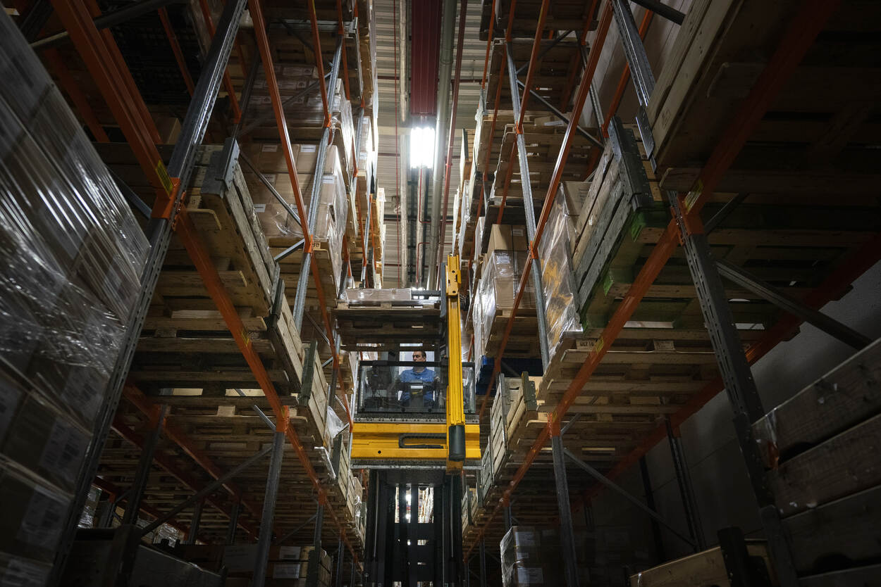In het magazijn staan hoge stellingen met goederen.
