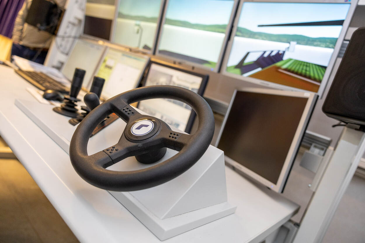 Het stuur van een simulator en daarachter een beeldscherm.