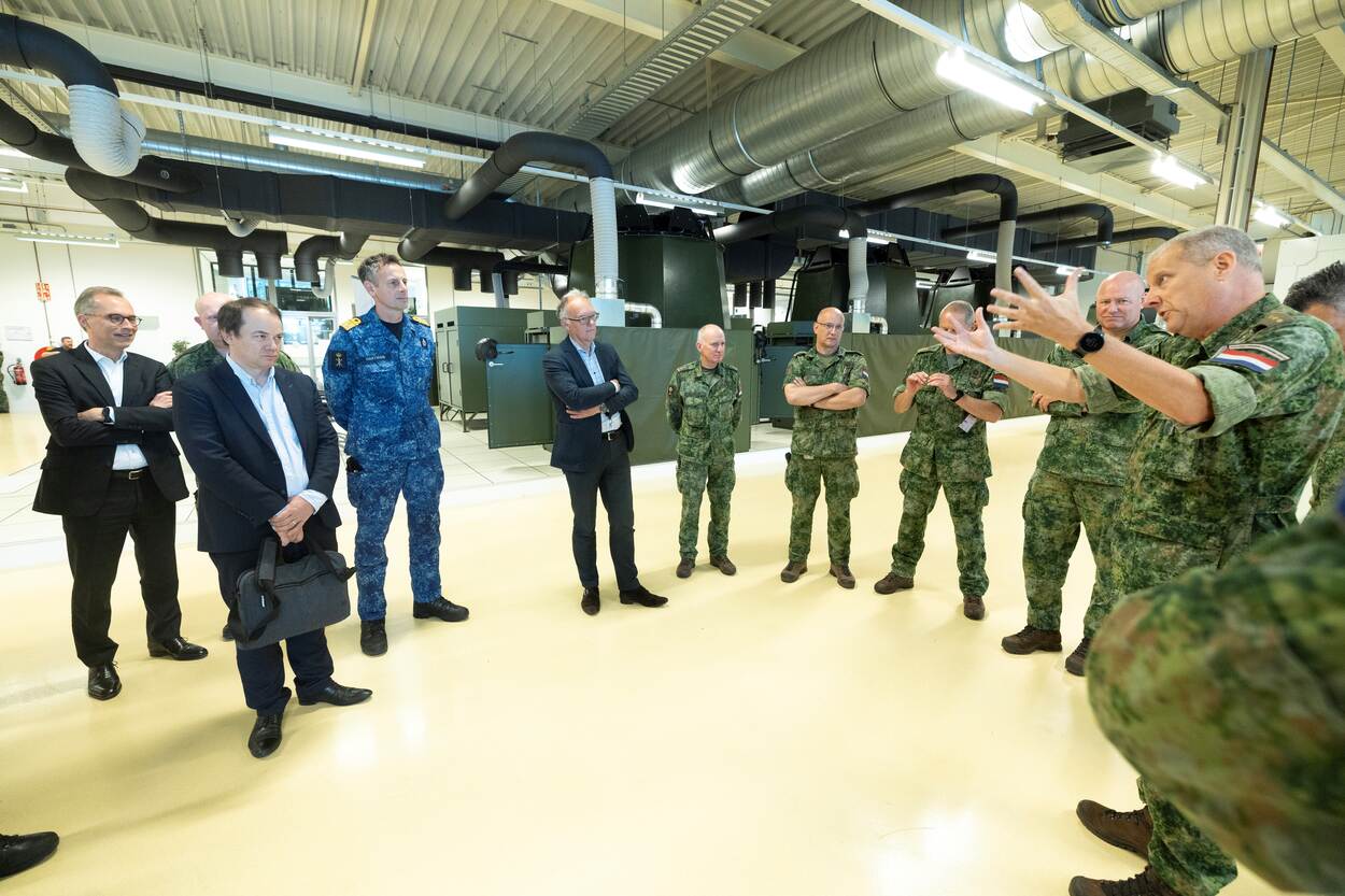 diverse genodigden in het simulatiecentrum die luisteren naar overste Liberg.