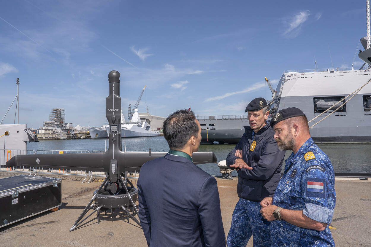 De CEO van ShieldAI in gesprek met viceadmiraal Hartman, commandant COMMIT, en viceadmiraal Tas, commandant Zeestrijdkrachten. Op de achtergrond staat de nieuwe V-BAT.
