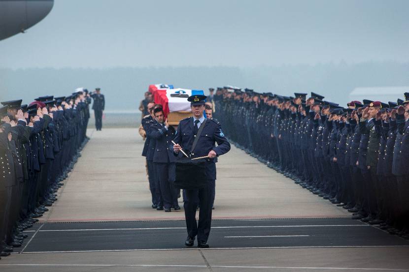 De 2 draagploegen lopen met de kisten door een erehaag van militairen.