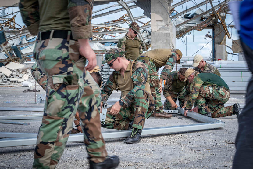Een groepje militairen werkt aan kapotte infrastructuur.