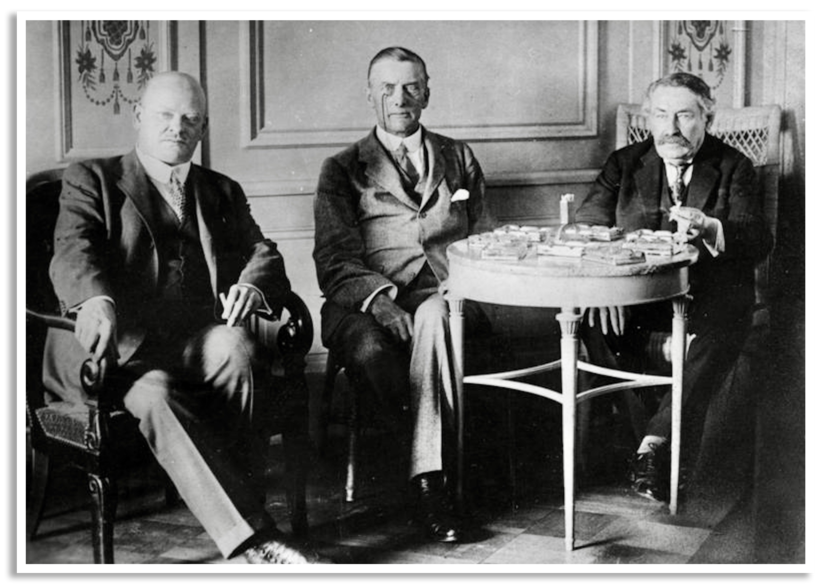 Zwart-witte staatsiefoto van drie hoofdrolspelers, met van links naar rechts Stresemann, Chamberlain en Briand.