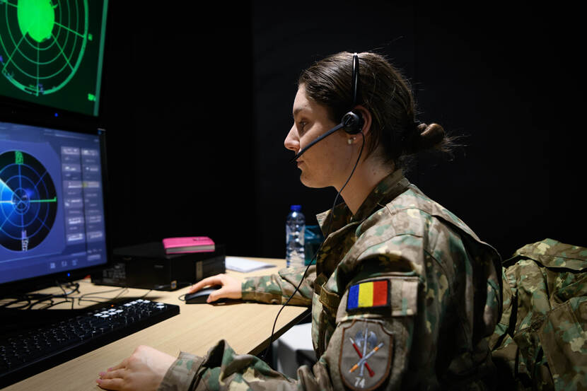 Een Roemeense militair zit achter een computer, waarop een radar te zien is.