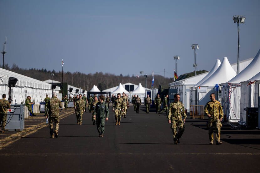 Militairen lopen langs de witte tenten op het terrein.