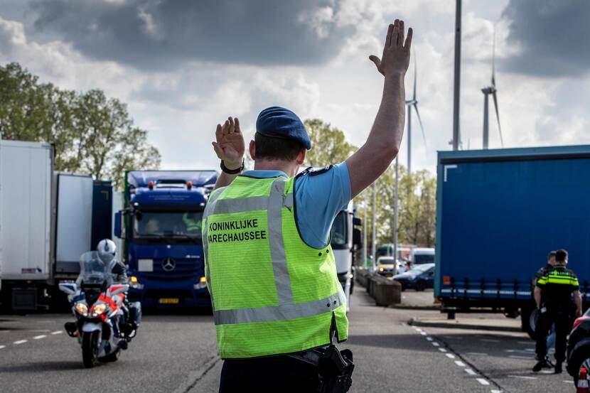 Een marechaussee gebruikt tijdens een grenscontrole handsignalen om een voertuig naar een controlevak te dirigeren.