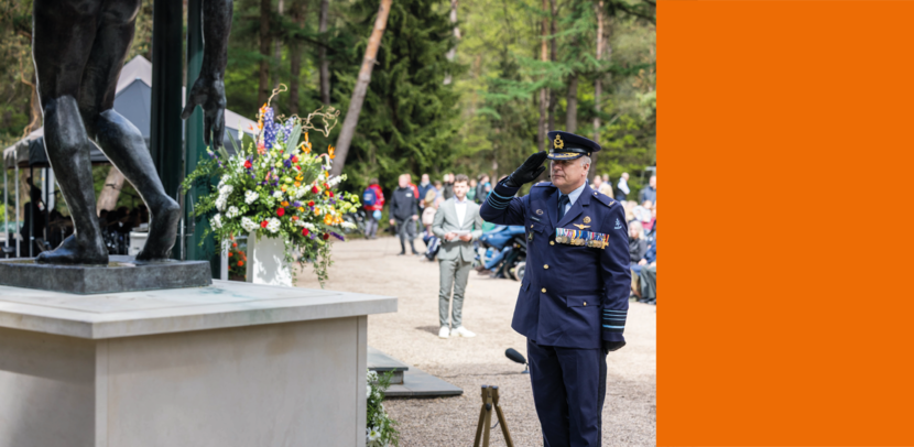 Commandant der strijdkrachten generaal Onno Eichelsheim brengt de militaire eregroet uit, staand voor een krans. Achter hem zitten mensen.