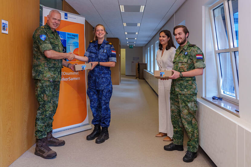 Militair overhandigt waarderingsgeschenk aan 3 collega’s.