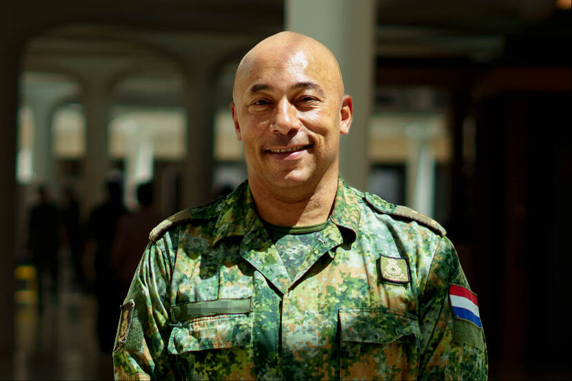 Militair kijkt lachend in de camera met zonlicht over zijn gezicht.