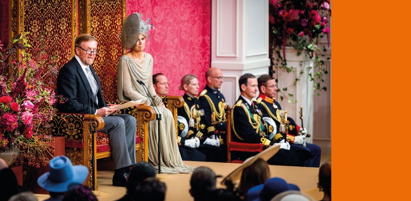 De Koning en Koningin op het schavot met daaromheen burgers en militairen in deftig tenue.