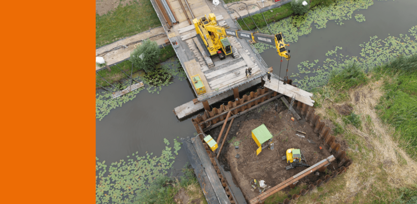 Een kraan verricht graafwerkzaamheden vanaf een plateau dat over het water ligt.