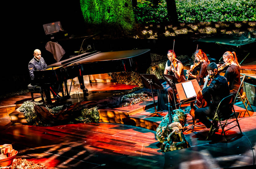 Militair achter de piano op podium met strijkkwartet.