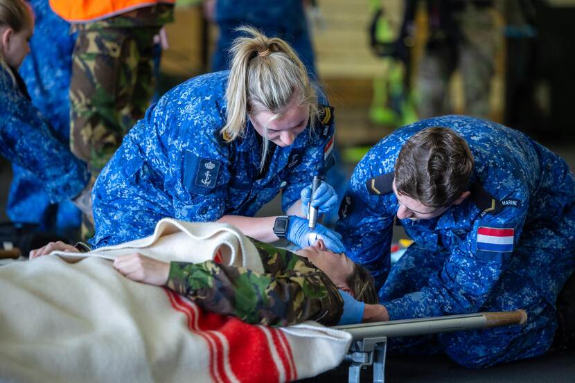 2 medische marinemensen onderzoeken een oefengewonde.