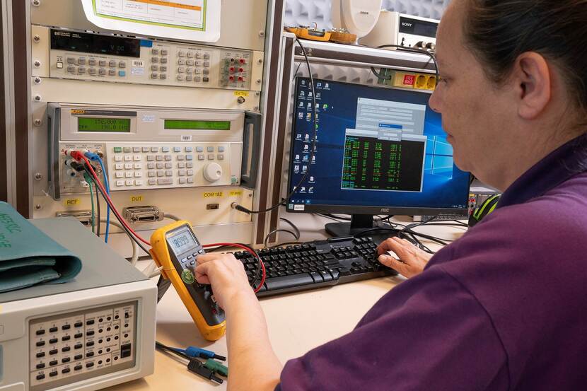 Een medewerker controleert een gele multimeter.