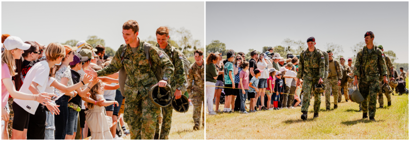 Mariniers die zojuist hun parachutesprong hebben gemaakt lopen langs een rij met publiek en geven high fives.