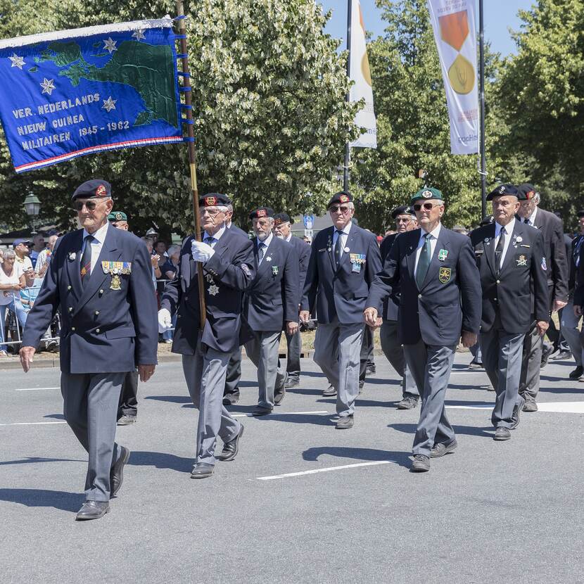 Marcherende veteranen met vaandel.