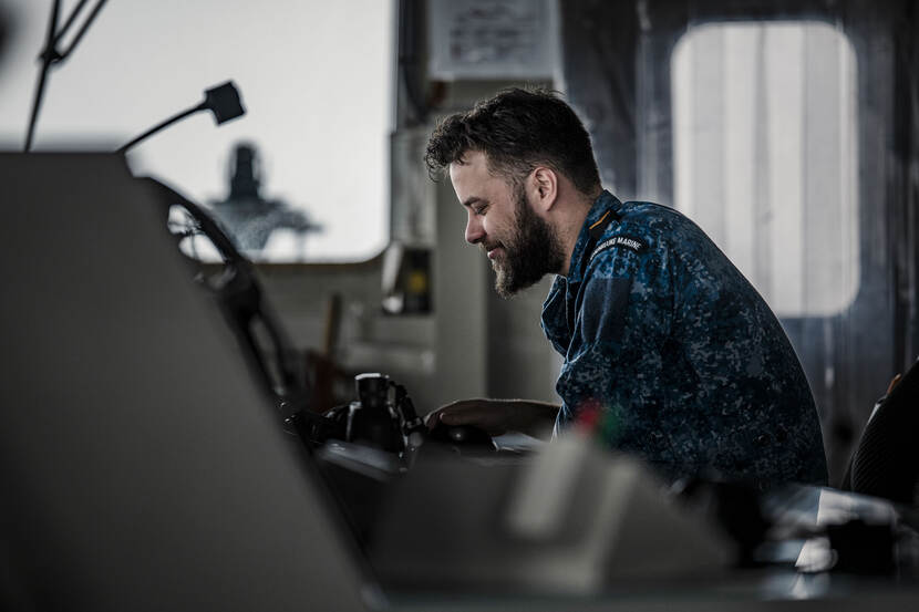 Een lachende collega op zijn werkplek aan boord.