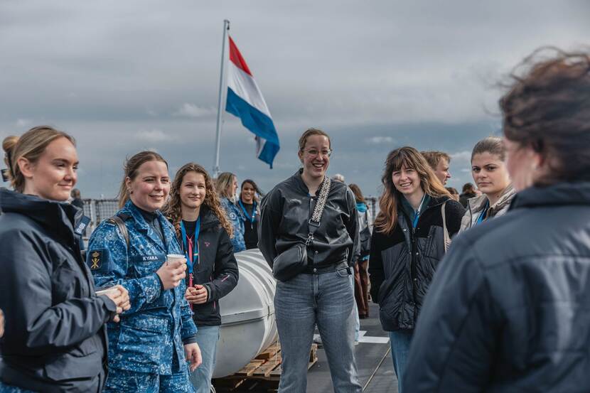 Meiden op het achterdek in gesprek met marinevrouwen.