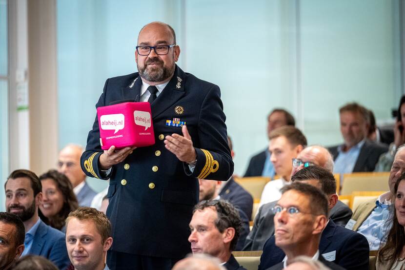 Een militair met ‘catchbox’ staat tussen het publiek tijdens de conferentie.