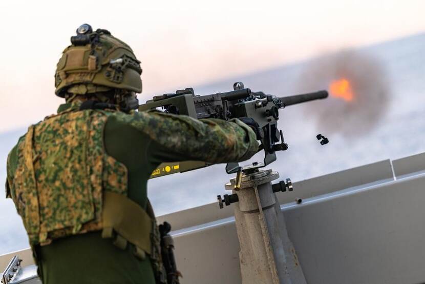 Een vurende militair aan boord van een schip