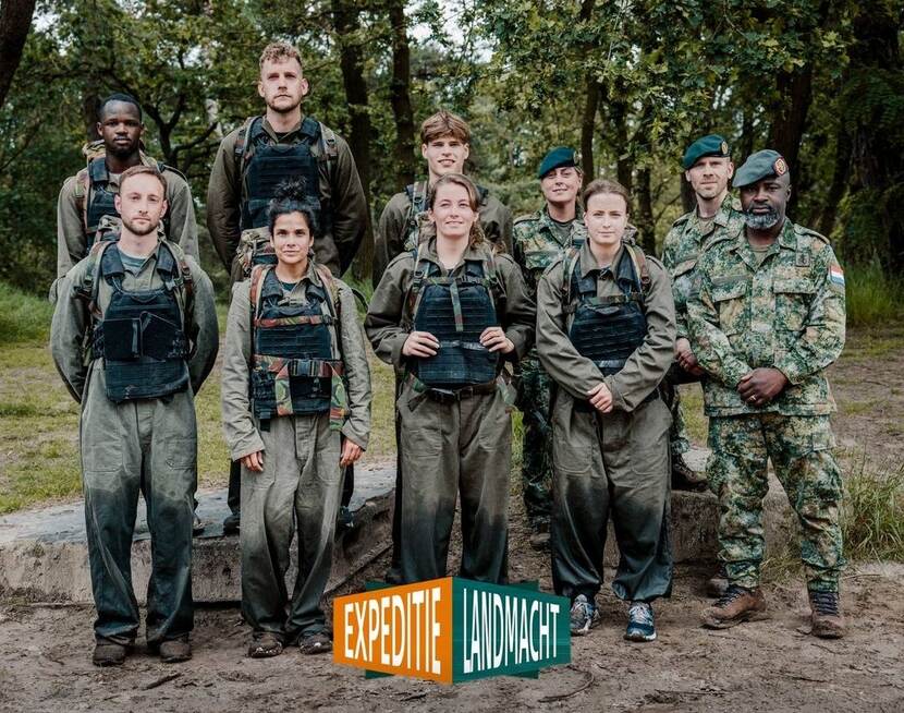 Een aantal deelnemers van Expeditie Landmacht poseert in het veld voor de camera.